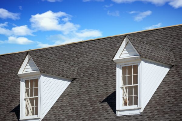Two White Wood Dormers On A Grey Shingle Roof Under Blue Sky